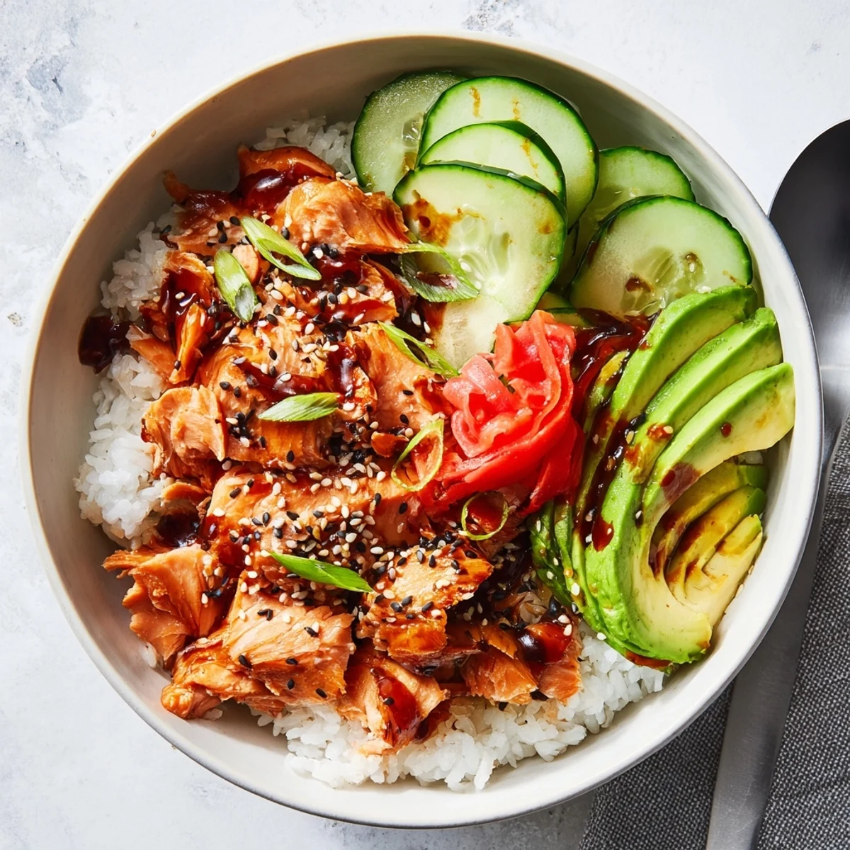 Delicious leftover salmon and rice bowl topped with fresh avocado and cucumber slices.  