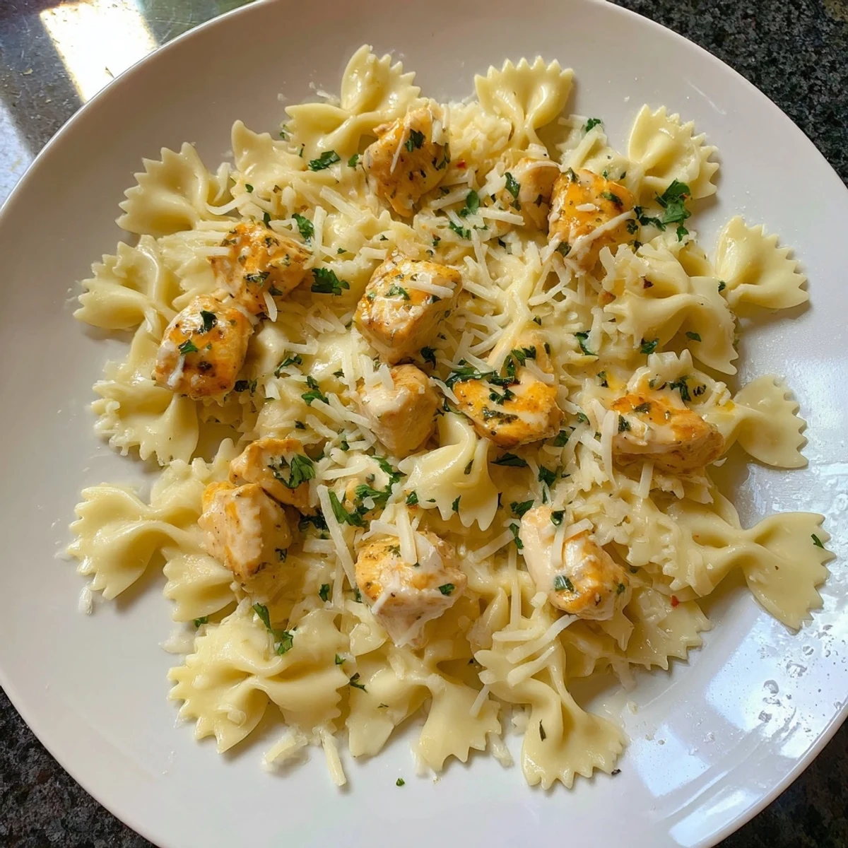 A close-up of mozzarella garlic butter chicken bowties showing the melted cheese and tender chicken pieces.