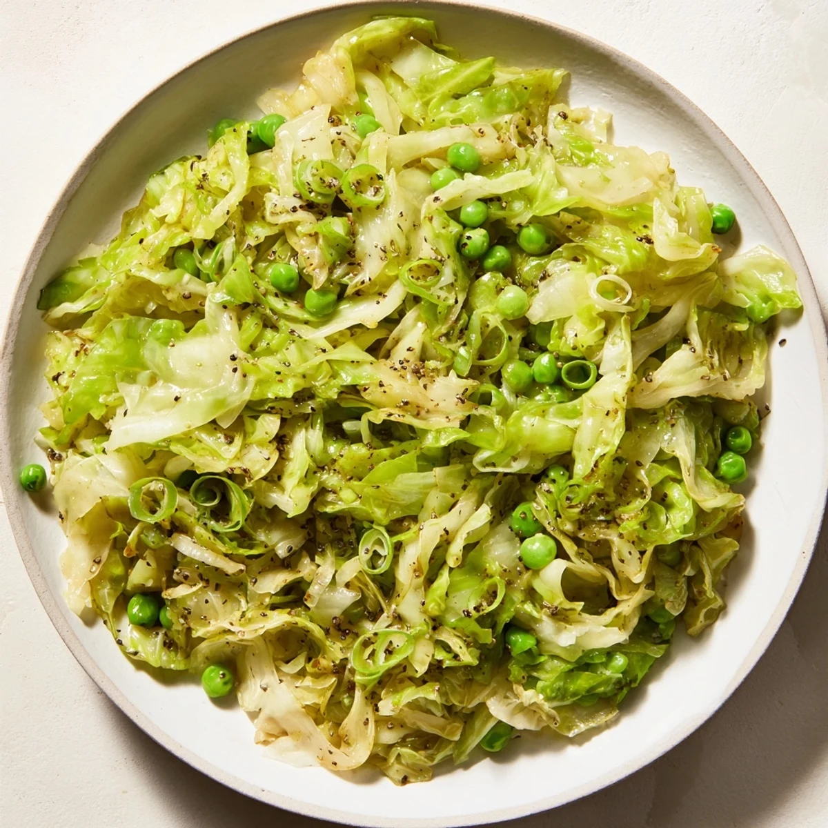 Tender cabbage stir-fry with garlic, soy sauce, and peas, ready to serve with steamed rice.