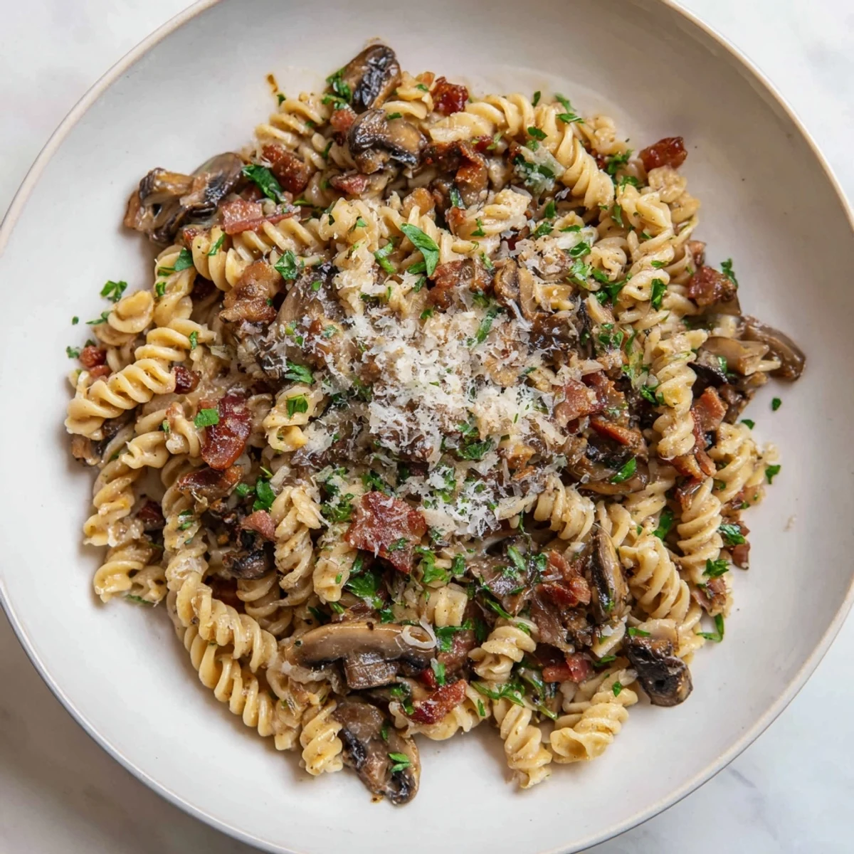 Fusilli with bacon, onions, and mushrooms: a steaming bowl of pasta, ready to eat.