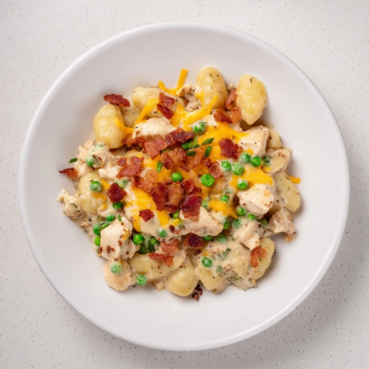 A steaming bowl of Creamy Crack Chicken Gnocchi features the rich, creamy sauce generously coating each pillowy gnocchi and garnished with green onions.