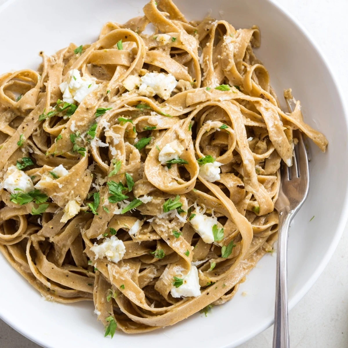 Golden-hued, delicious Skinny Alfredo Garlic Parmesan Snowy Pasta, ready to serve with a light garlic-infused cream sauce.