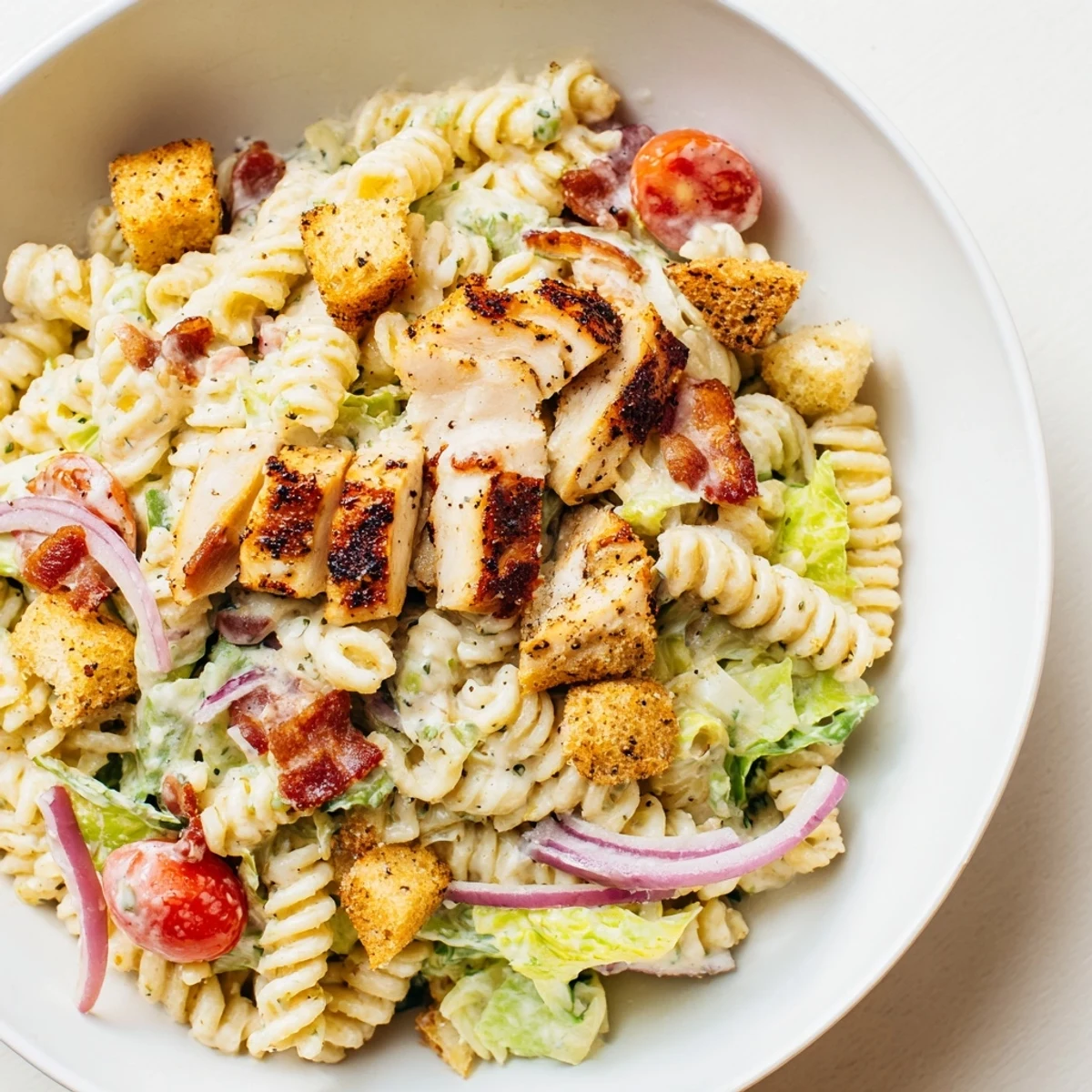 Fresh, vibrant Chicken Caesar Pasta Salad: rotini tossed with grilled chicken, bacon, and romaine lettuce.
