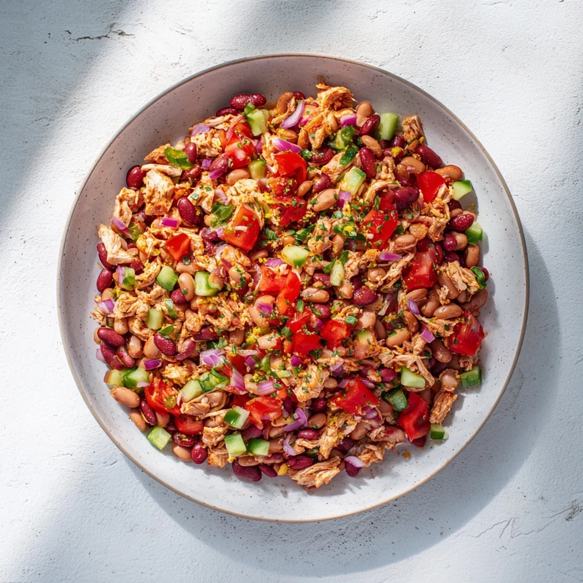 A refreshing bowl of Dense Bean Salad with Lemon-Dill Chicken, drizzled with zesty dressing, looks delicious.