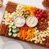 Explore this delicious Urban Grid appetizer with cubed cheeses, olives, and vibrant fresh vegetables on the grid.