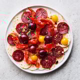 Vivid image of The Crimson Tide appetizer: Red chorizo, peppers, and cherries, ready to enjoy.