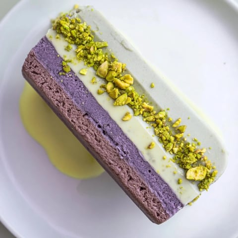 Creamy Ube & Pistachio Ice Cream Bars drizzled with condensed milk and chopped nuts.  