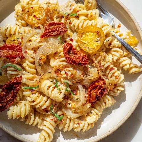 Creamy Baked Feta Pasta with caramelized onions and sun-dried tomatoes ready to serve.  