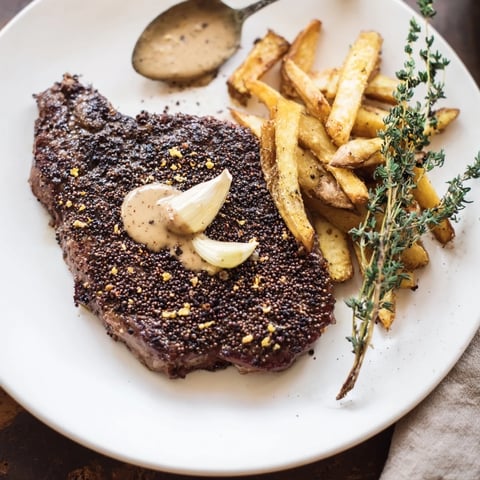 Classic Peppercorn Ribeye alongside golden, crispy fries; imagine tender steak and a rich sauce.