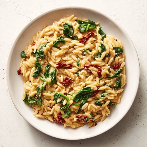 Steaming Creamy Tuscan Orzo Bowl, featuring vibrant spinach and sun-dried tomatoes, a perfect Italian dinner.