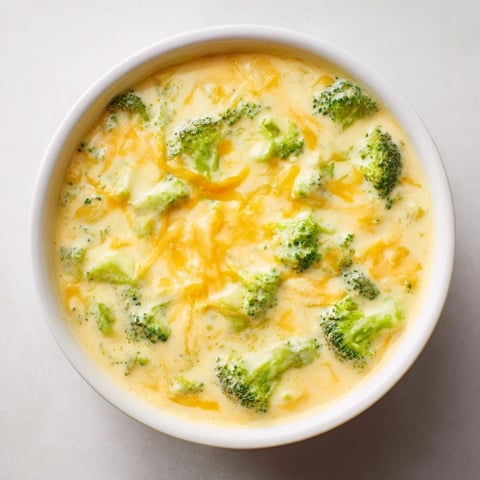 Steaming hot bowl of Broccoli Cheese Soup with melted cheddar, perfect for a cozy dinner.