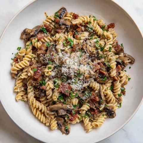 Fusilli with bacon, onions, and mushrooms: a steaming bowl of pasta, ready to eat.