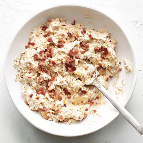 Close-up shot shows creamy Caramelized Onion and Bacon Dip, perfect for dipping crackers at a party.