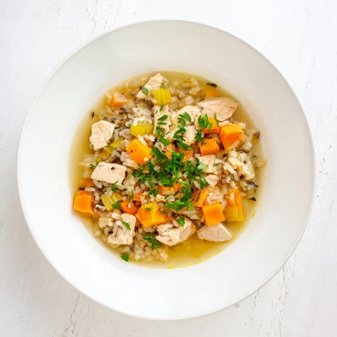 Steaming bowl of Quick Chicken and Wild Rice Soup, garnished with vibrant parsley; a comforting dinner.