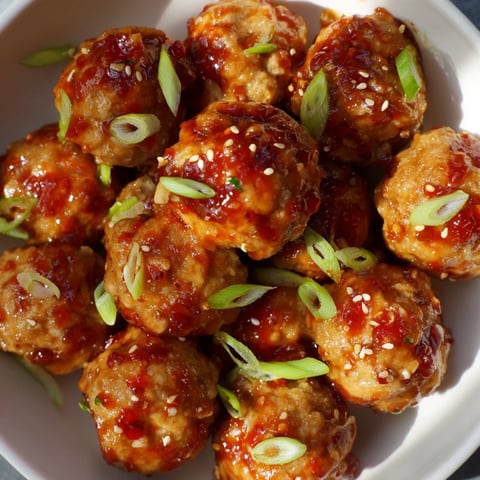 Golden-brown Spicy Honey-Glazed Chicken Meatballs glistening in a sweet and spicy sauce.