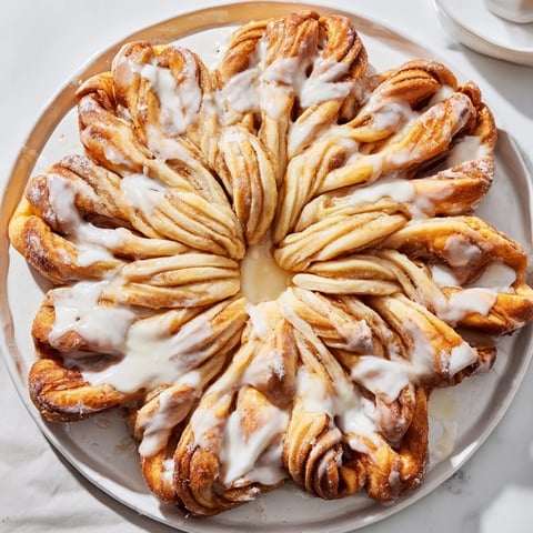 Giant snowflake sweet roll centerpiece, golden brown and glistening with icing, perfect for a festive occasion.
