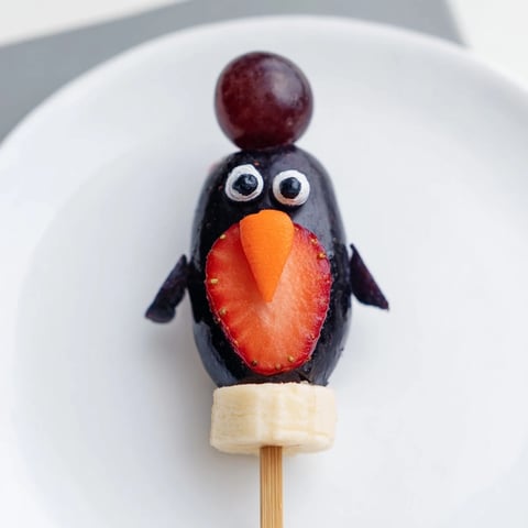 Vibrant Penguin Fruit Skewer Army featuring strawberries, grapes, and blueberries on a fun, colorful platter.