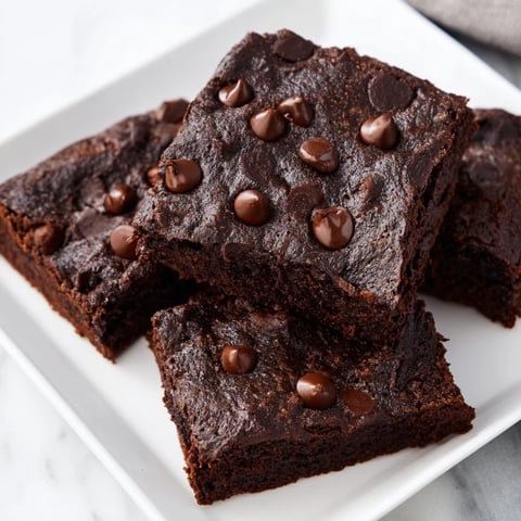 Warm, fudgy Greek yogurt brownies topped with melted chocolate chips, ready to slice and serve.