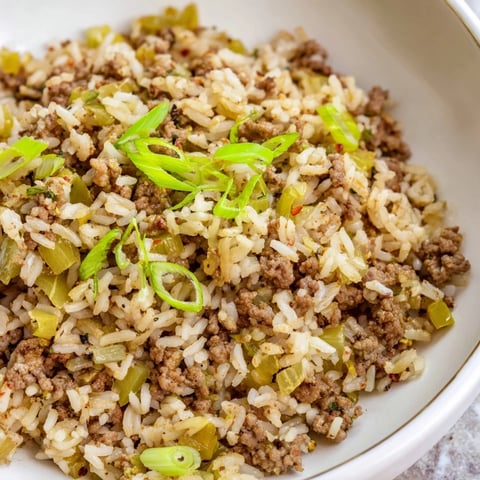 Steaming, savory Cajun Dirty Rice topped with fresh green onions; a Southern comfort food classic.