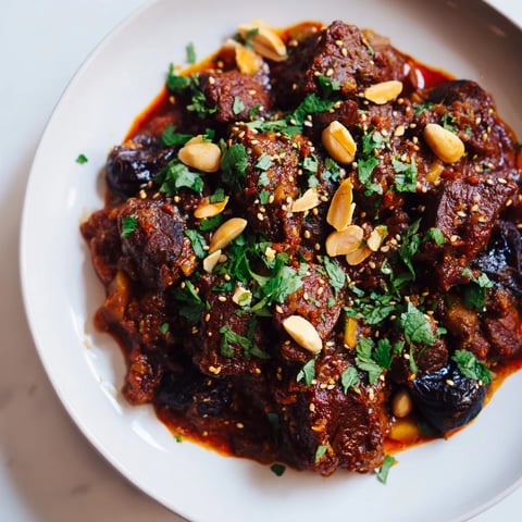 Close-up of a steaming Moroccan Lamb Tagine, showcasing tender lamb and sweet prunes.