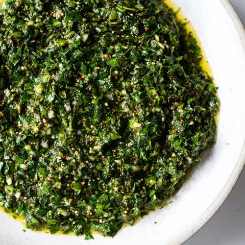 Image: A fish fillet coated in vibrant green Moroccan Chermoula Marinade, ready for grilling.