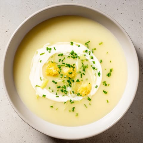 A close-up of a bowl of warm, smooth Potato Leek Soup, ready to eat with crusty bread.