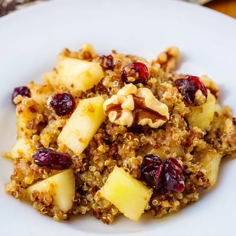 Golden Apple Cinnamon Quinoa Bowl, beautifully garnished with nuts and fruit, ready for a delicious breakfast enjoyment.