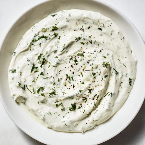 A close-up view of creamy Greek Yogurt Herb Dip, seasoned with garlic, lemon, ready to eat.