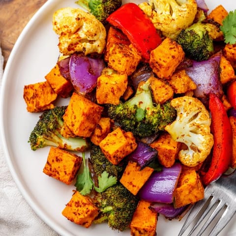 A close-up view of the vibrant Anti-Inflammatory Turmeric Roasted Vegetables, with caramelized red bell peppers and onions glistening with olive oil and herbs.