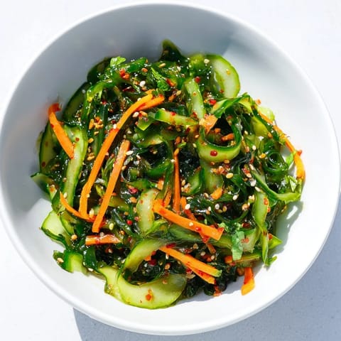 A refreshing bowl of Seaweed Salad garnished with toasted sesame seeds and fresh cilantro, served as a light appetizer.
