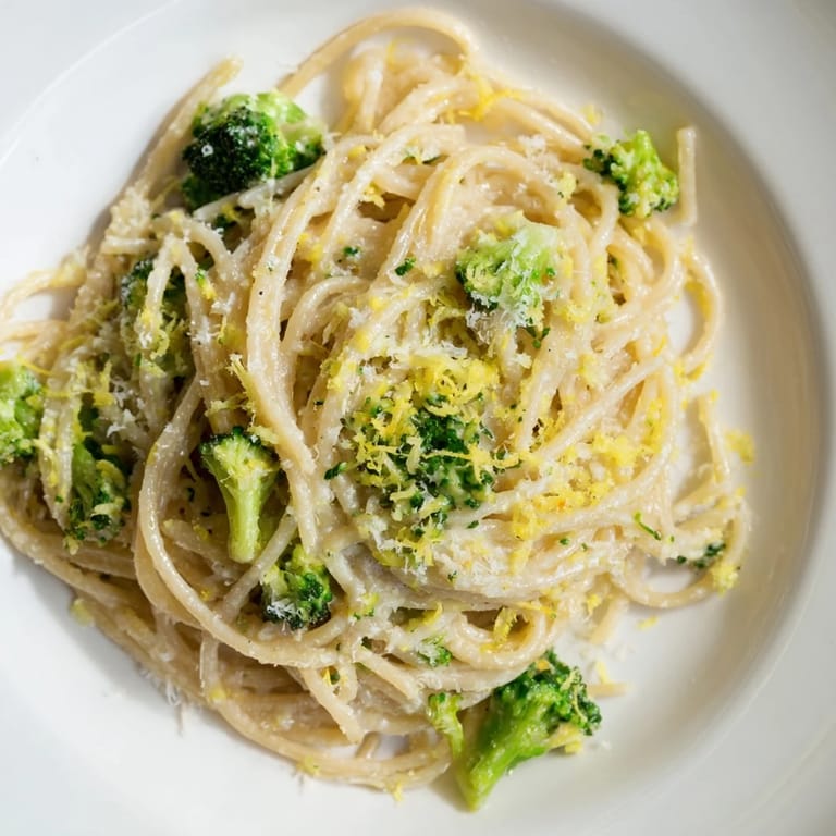 Serving suggestion for one-pot lemon broccoli pasta: plated with extra Parmesan, a lemon wedge, and crusty bread for easy weeknight dinner.