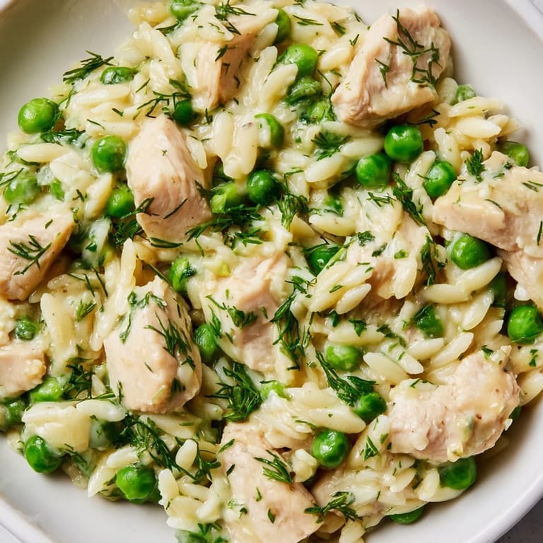A finished Lemon Herb Chicken Orzo Skillet, garnished with parsley and dill, steam rising from the one-pan dinner.  