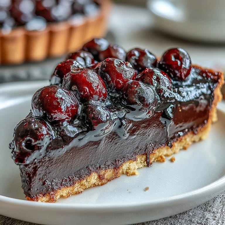Fresh Black Currant Fruit Tart garnished with mint, showcasing a vibrant crown of mixed berries and a dusting of powdered sugar.