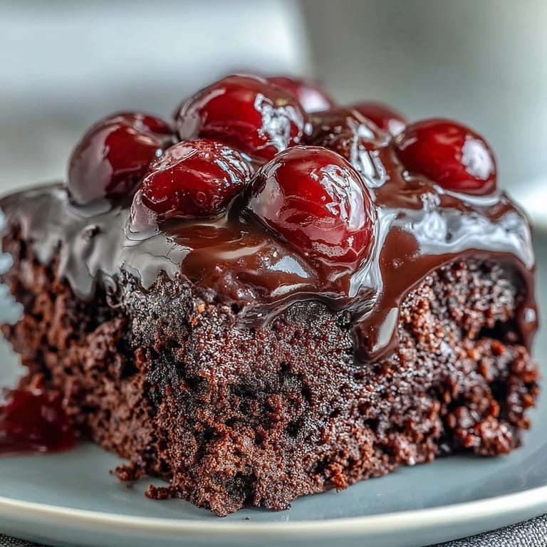 Moist, chocolatey Cherry Cola poke cake layered with pudding and cream.