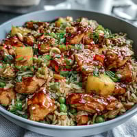 A vibrant bowl of Hawaiian pineapple chicken fried rice with juicy pineapple chunks and tender chicken pieces mixed with colorful vegetables and fluffy jasmine rice.