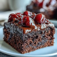 Decadent Cherry Cola Chocolate Poke Cake with fluffy whipped cream and bright cherries.